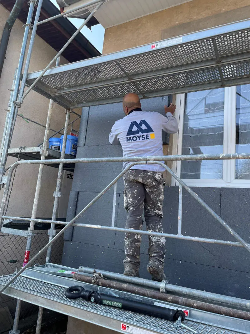 Un membre de l'équipe Moyse 3D en train de poser l'isolation thermique par l'extérieur d'un bâtiment